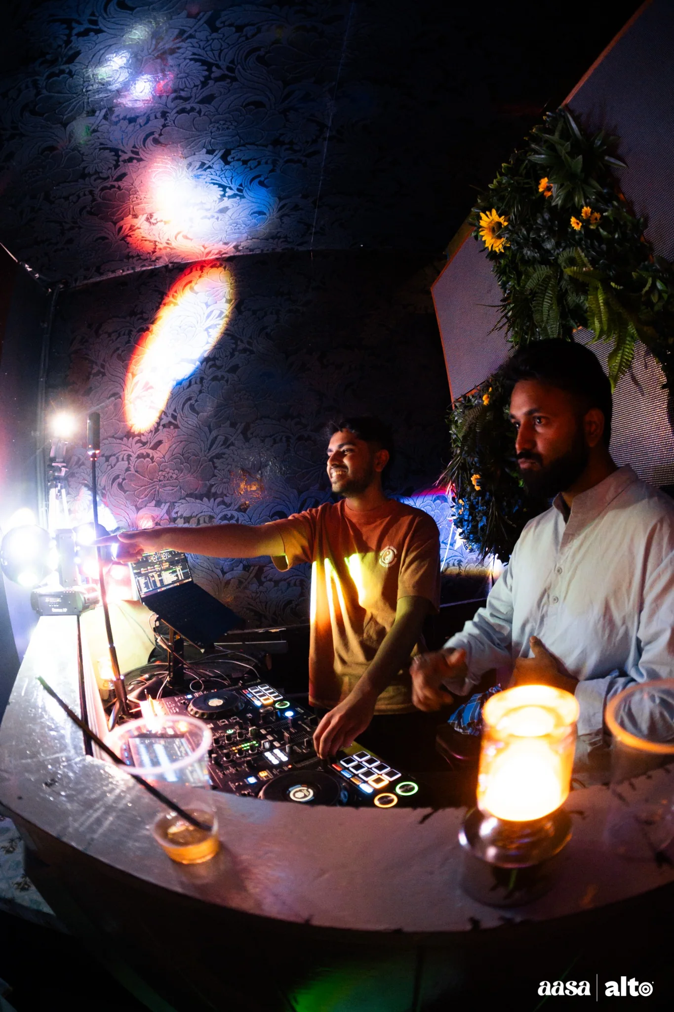 DJ Bhargav smiling at the booth under colourful lights