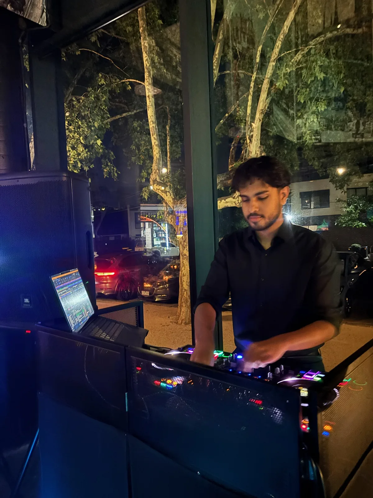 DJ Bhargav performing at night through a venue window