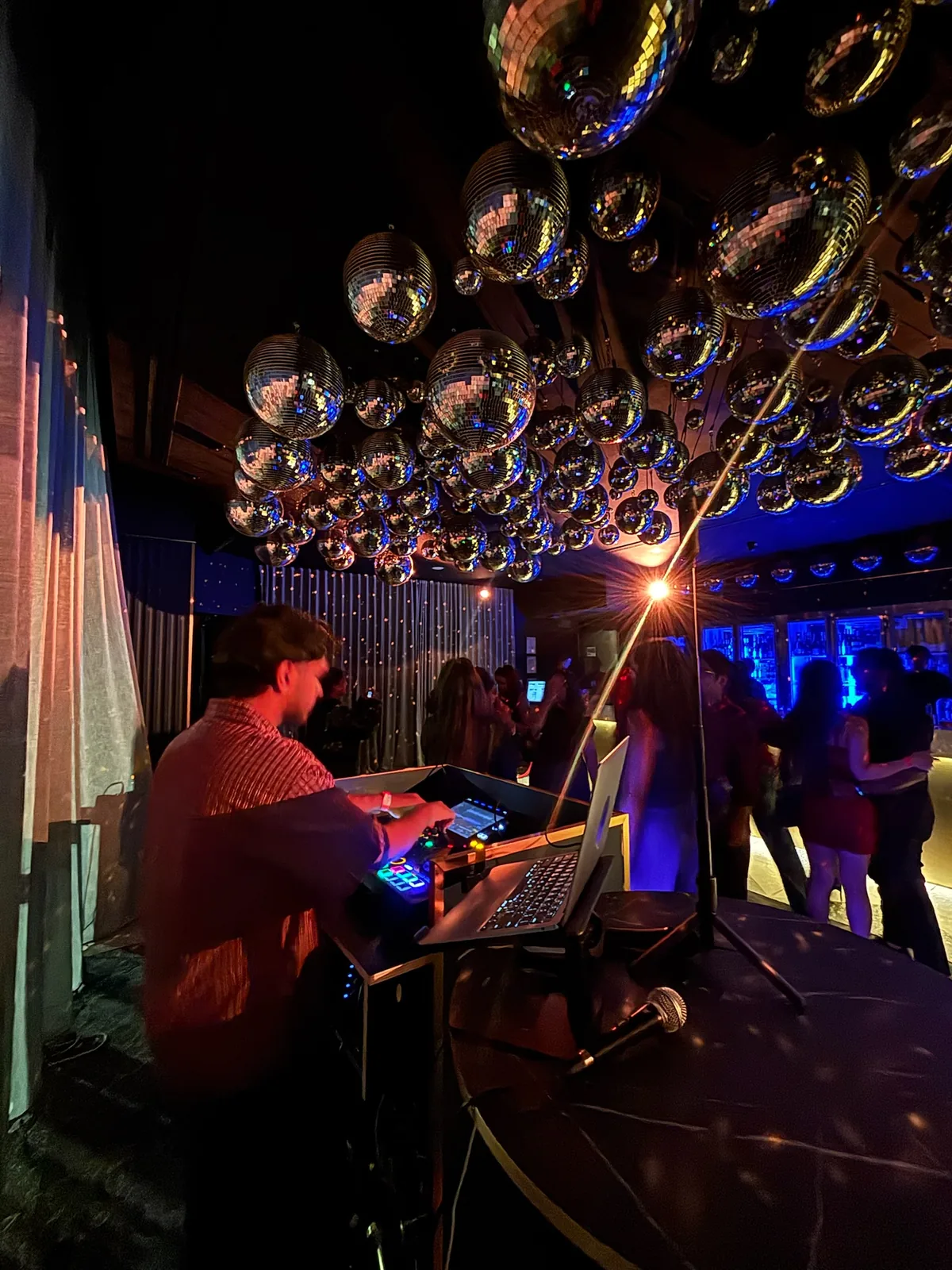 DJ booth beneath cluster of disco balls