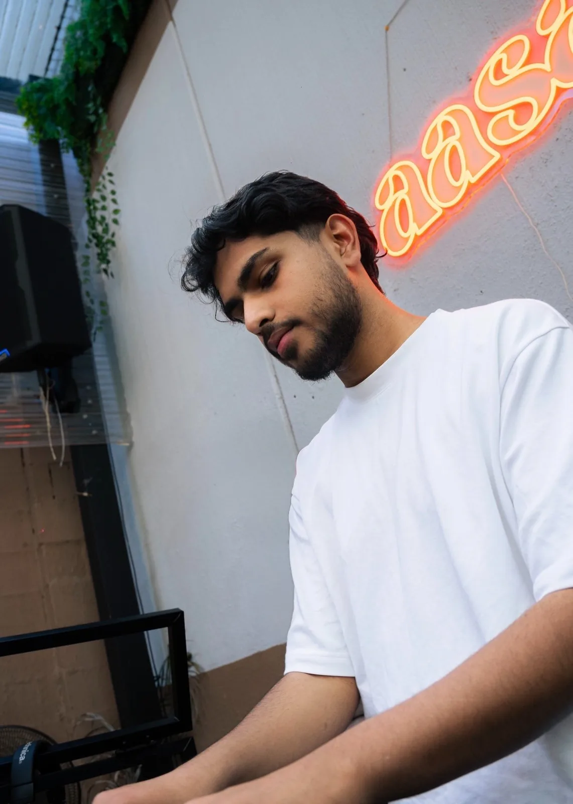 DJ Bhargav with neon signage backdrop