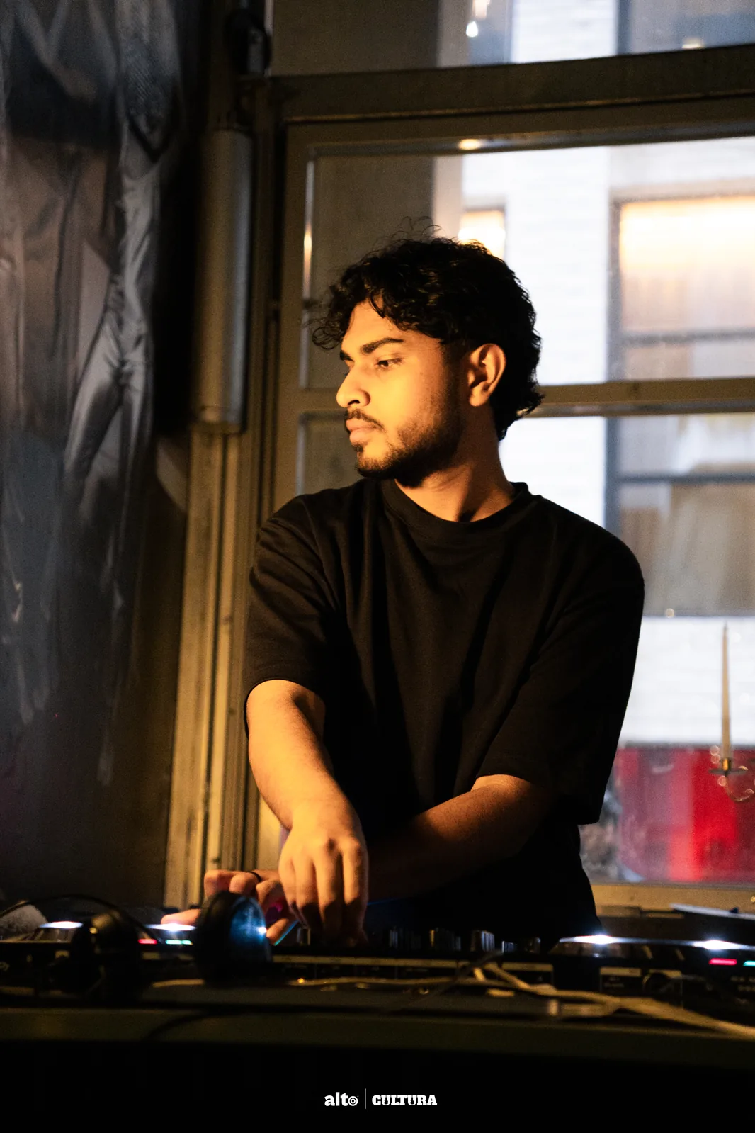 DJ Bhargav in earth-tone tee, behind a Pioneer controller
